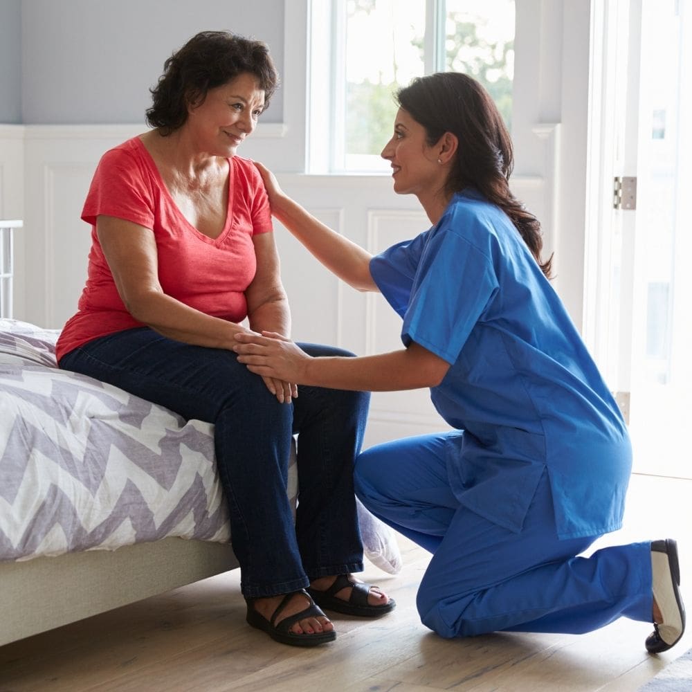 A nurse comforting a woman sitting on a bed.