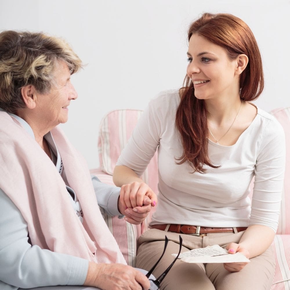 A nurse comforting a woman sitting on a bed.