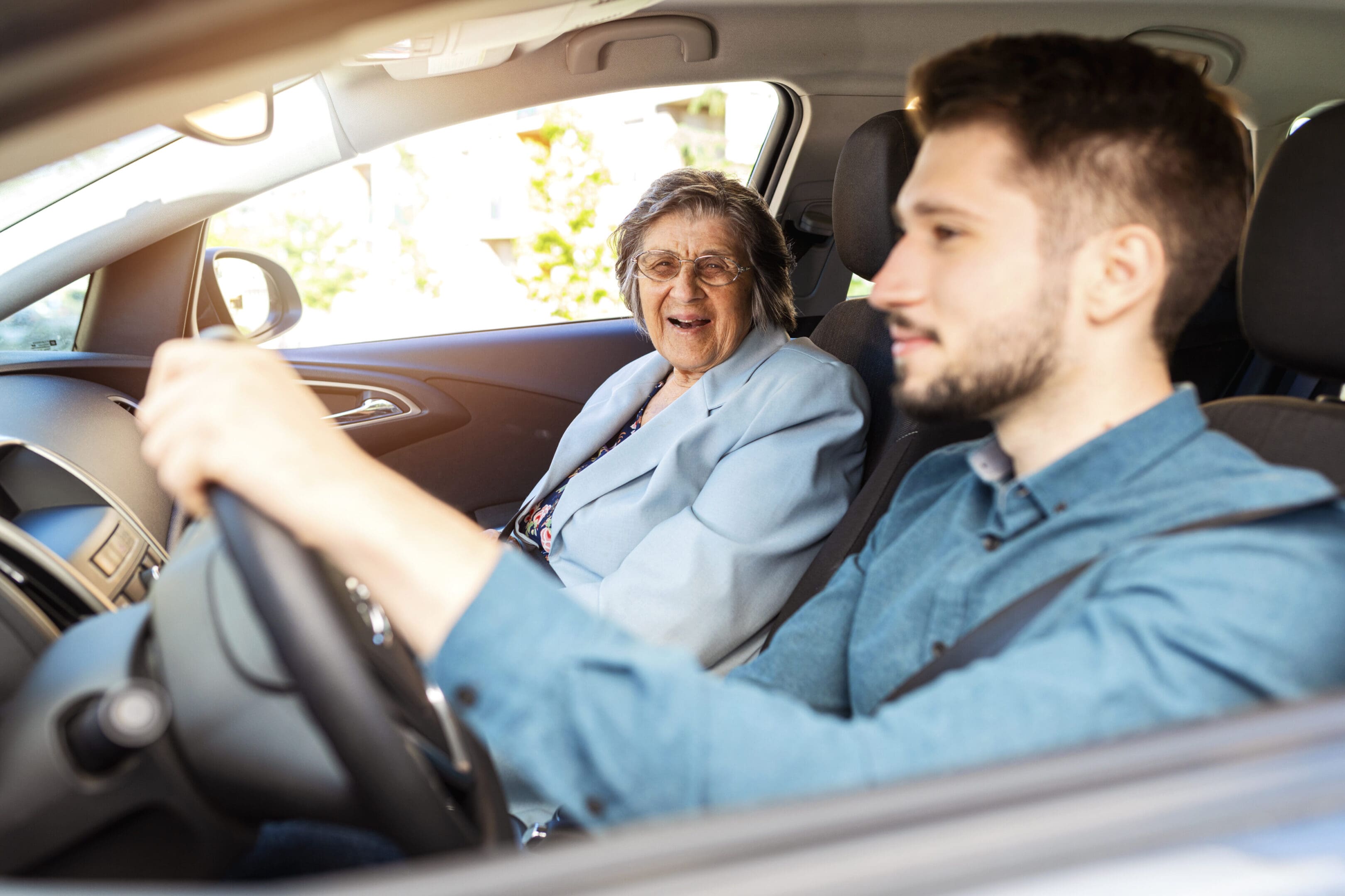 Young man spending time together with his grandmother.He driving grandma by the car.