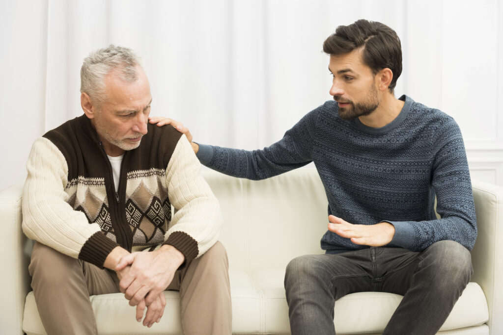 young-guy-with-hand-shoulder-aged-sad-man-sofa